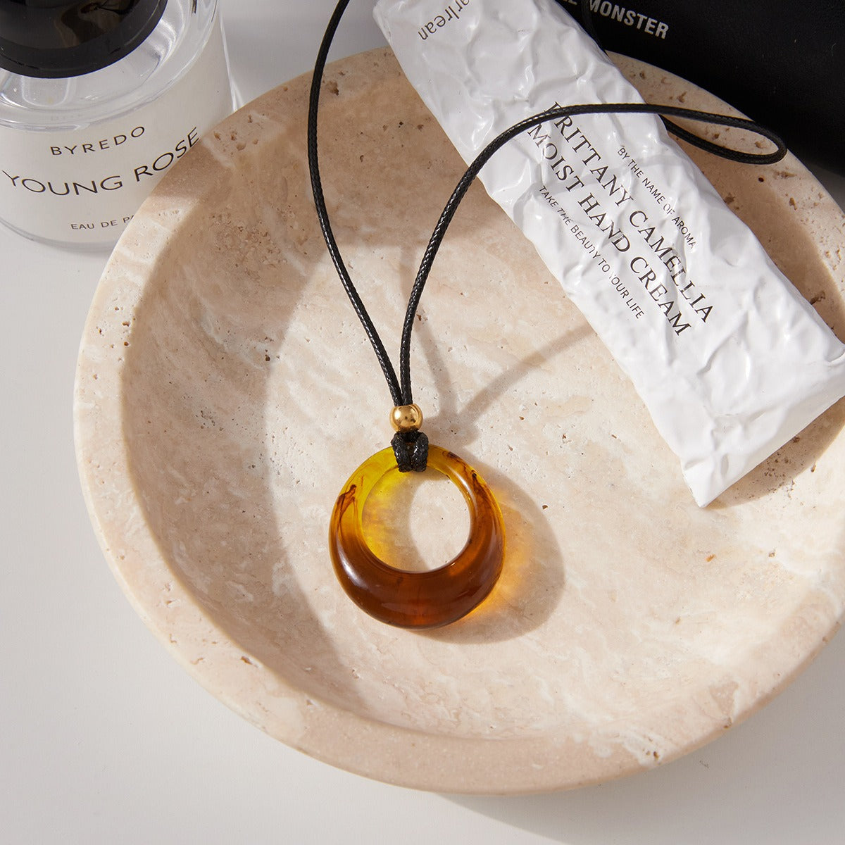 Amber-colored resin long necklace with a black cord.