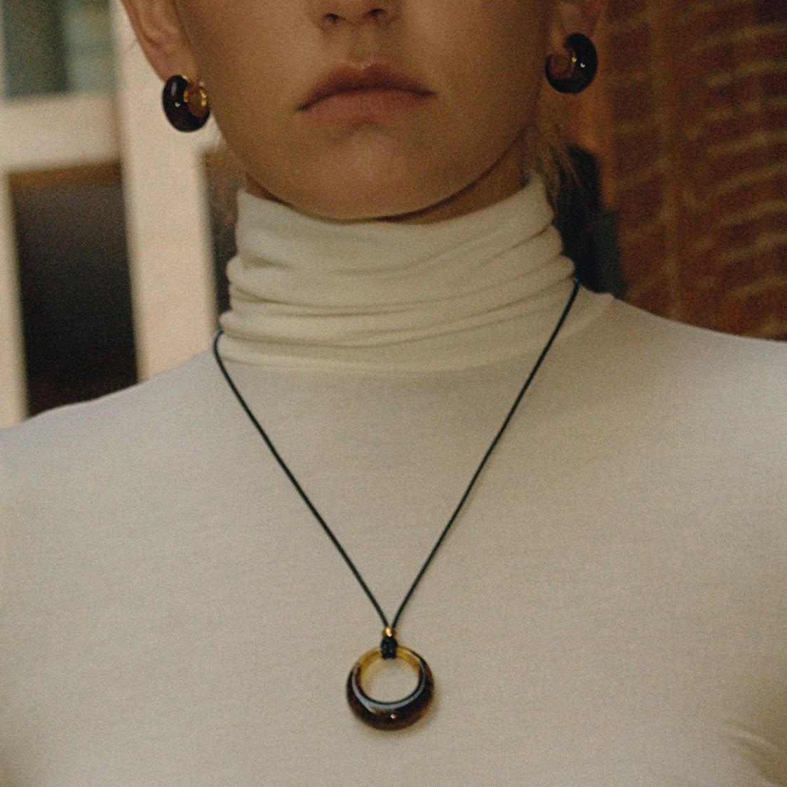 Amber-colored resin long necklace with a black cord.